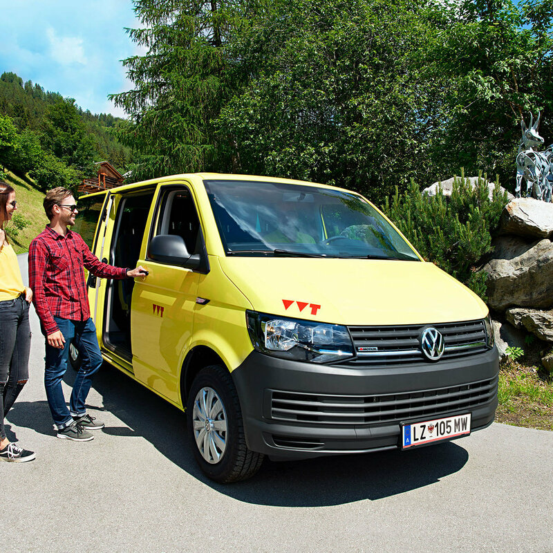 Auf dem Bus sind zwei Wanderer zu sehen, die gerade in das gelbe Wanderbus einsteigen