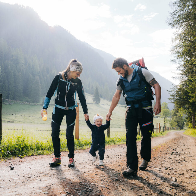 Eine Mann und eine Frau mit ihrem kleinen Kind dazwischen wandert im Kristeinertal.