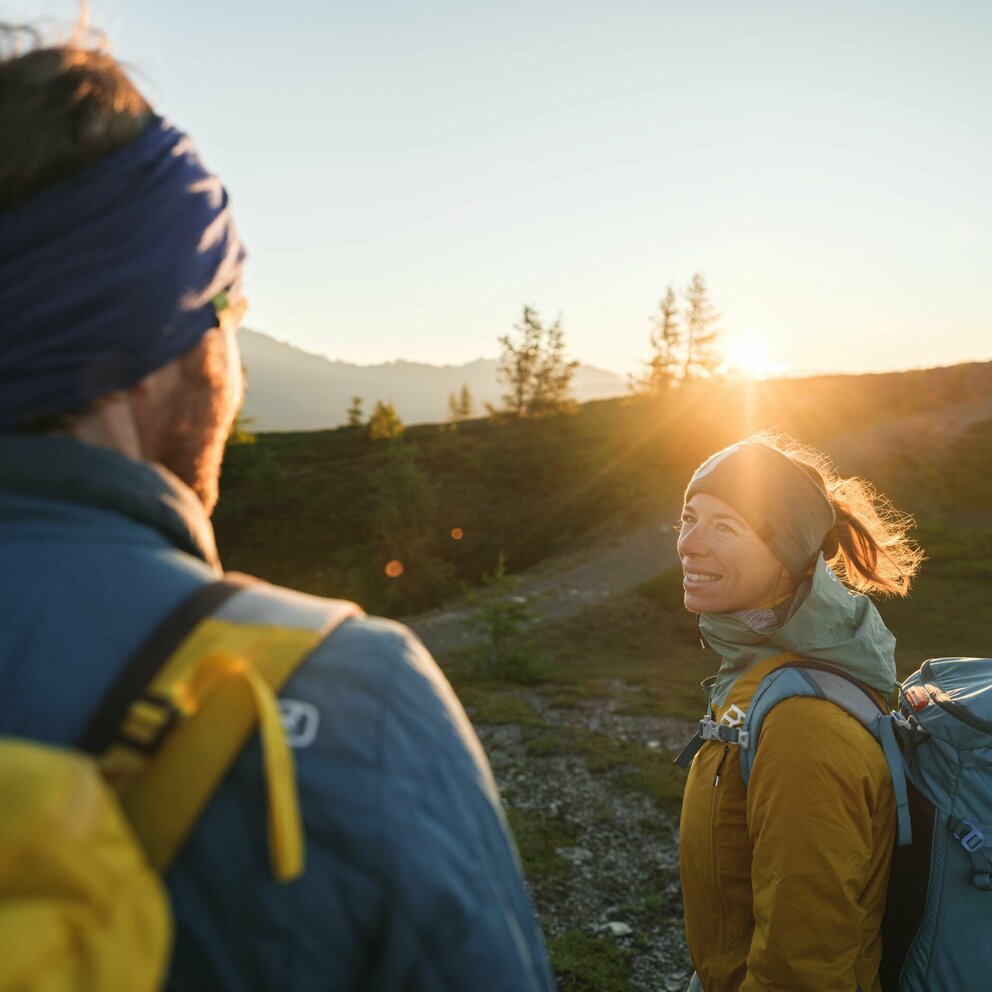Sonnenaufgang mit einem Pärchen, welches sich anlächelt, im Vordergrund.