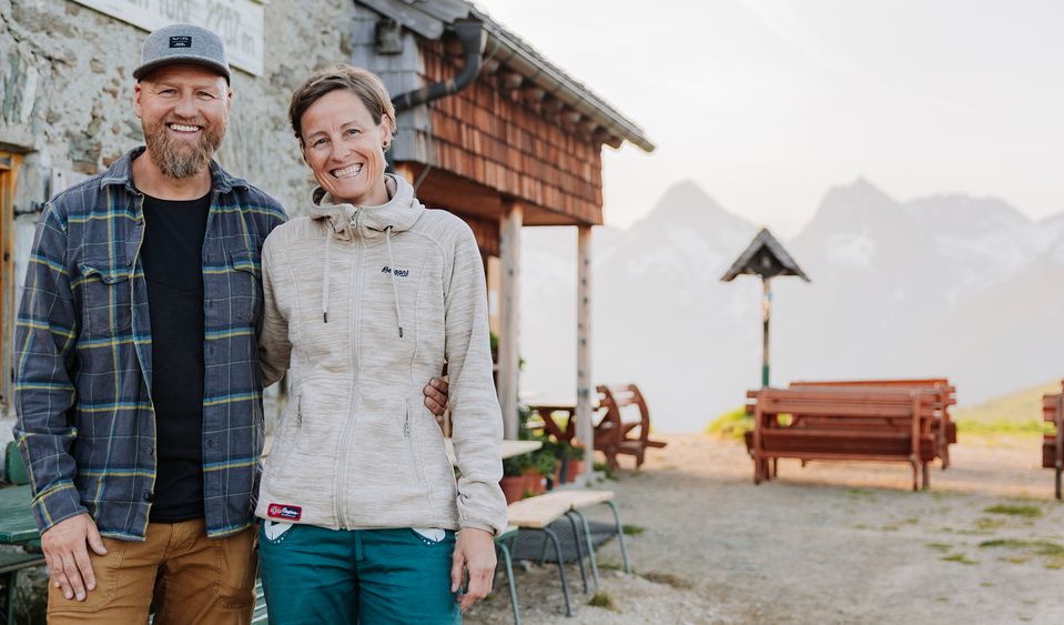 Das Gastgeber der Hütte am Kals-Matreier-Törl lächeln freundlich in die Kamera, dahinter die Bergwelt Osttirols.