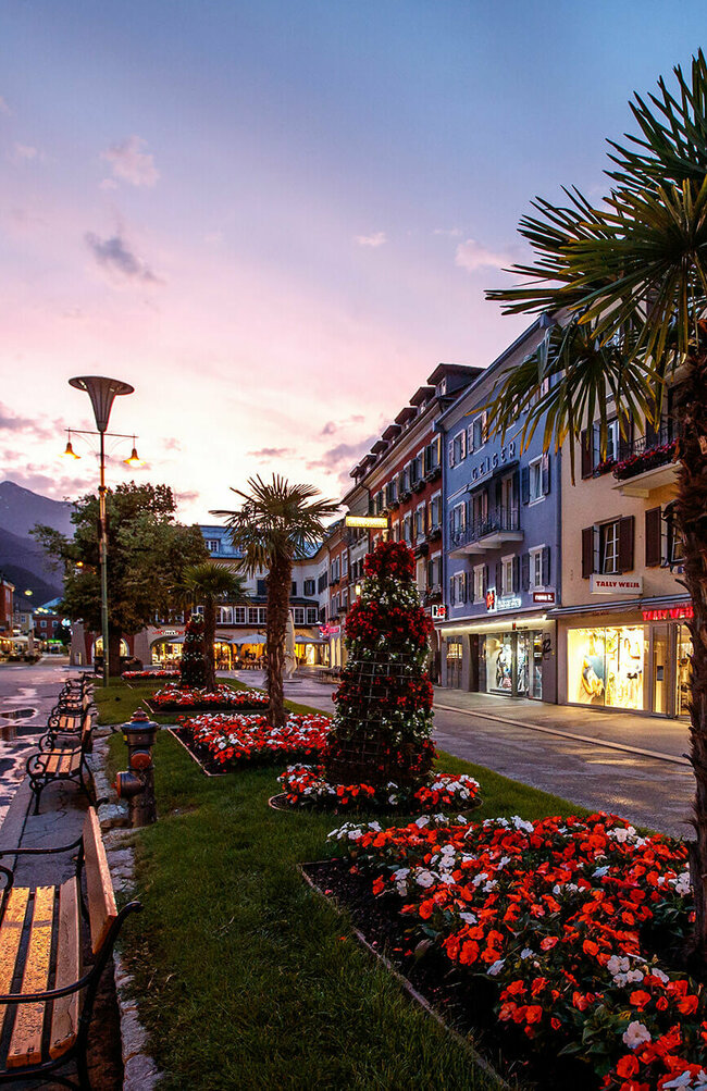 Die Blumenbeete und Bänke am Lienzer Hauptplatz in der Abenddämmerung. Der Himmel färbt sich leicht rosa.