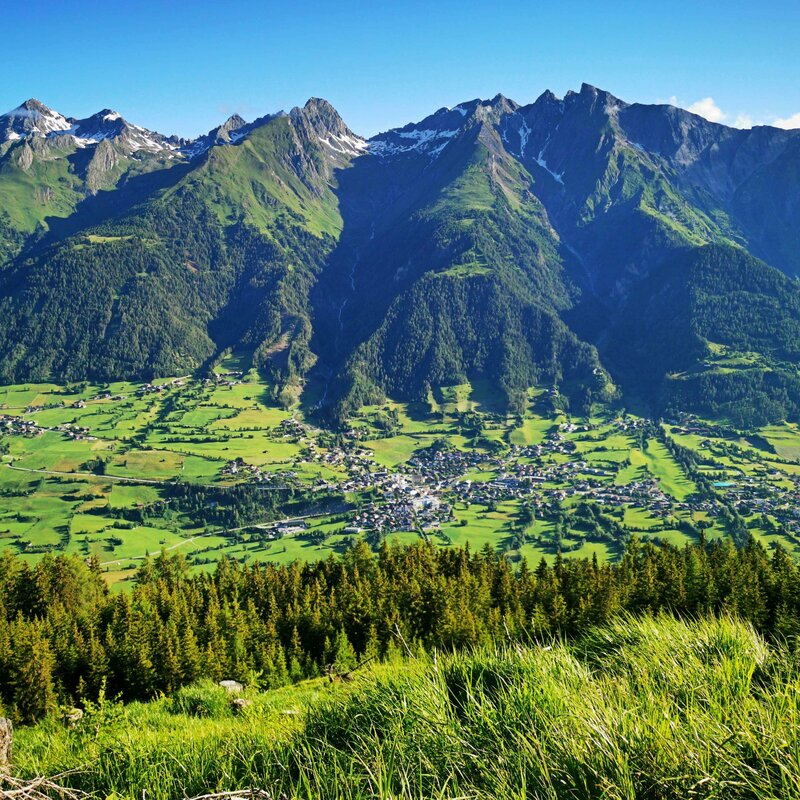 Panorama Virgen Panoramaaussicht auf die Gemeinde Virgen mit saftig grünen Wiesen und Wäldern drum herum. Auf den Berggipfeln liegt noch vereinzelt Schnee.