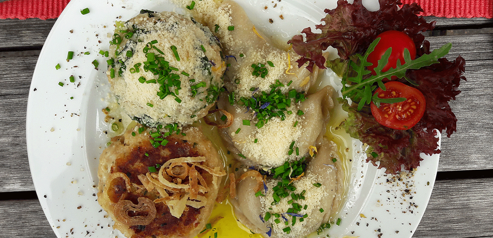 Ein Teller voller Schlipfkrapfen und zwei weiteren Knödelarten in Nahaufnahme.