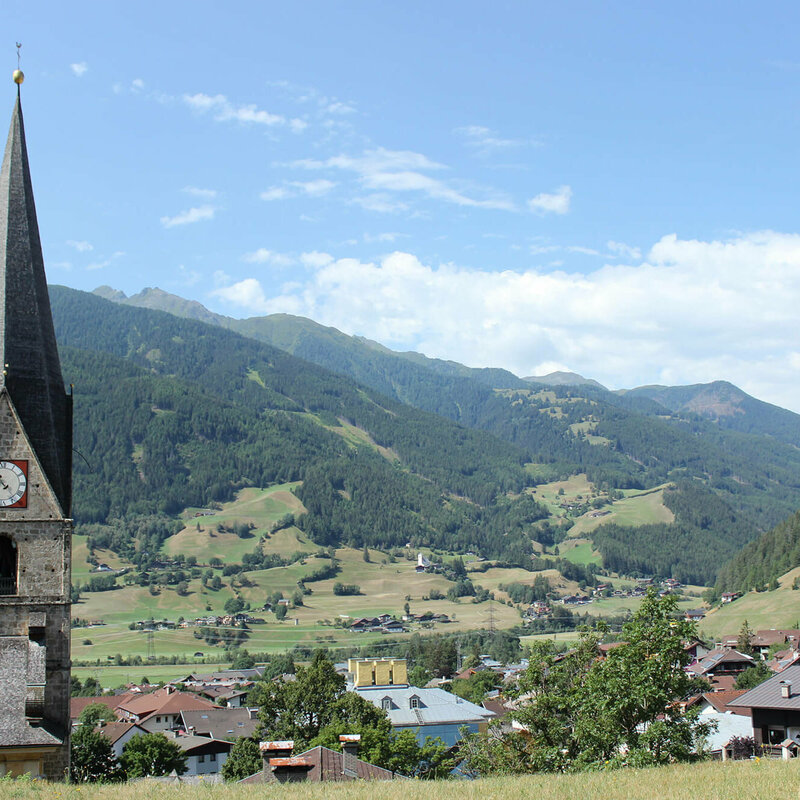 Matrei Blick auf den Kirchturm und die umliegende Landschaft in Matrei, an einem sonnigen Tag.