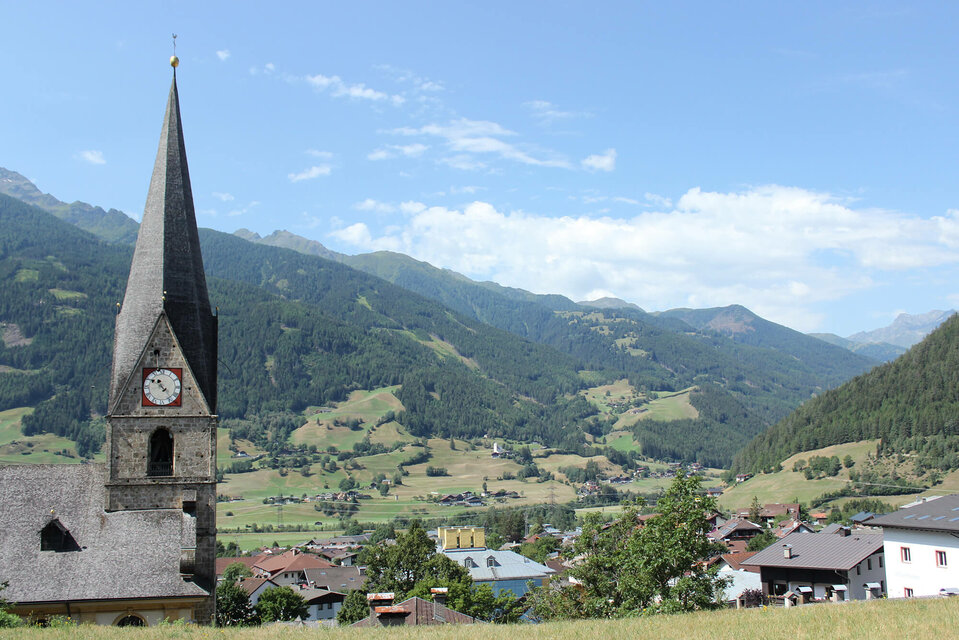 Matrei Blick auf den Kirchturm und die umliegende Landschaft in Matrei, an einem sonnigen Tag.