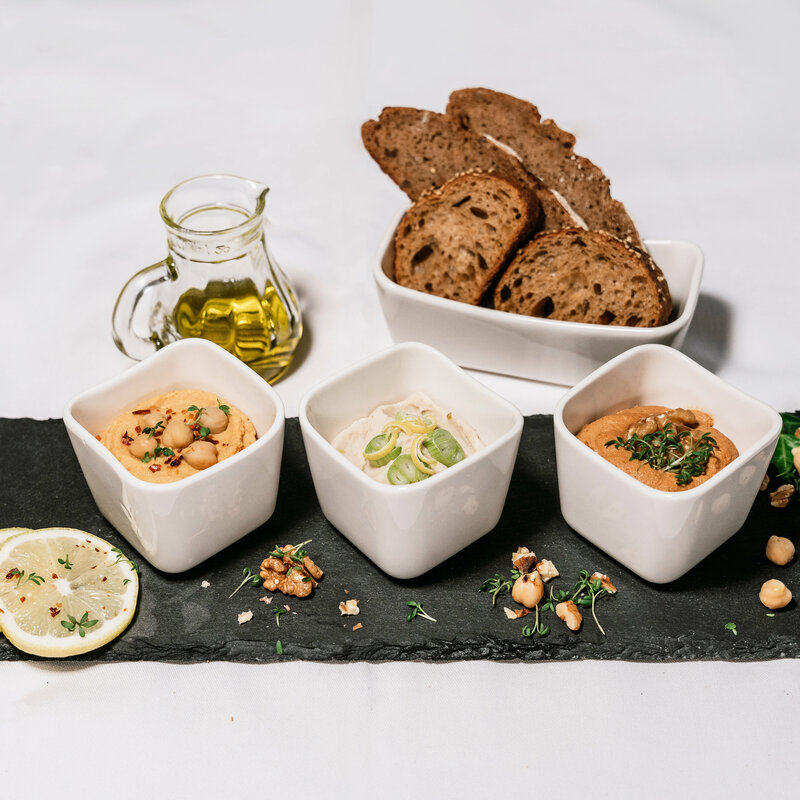 Schieferplatte mit Aufstrichvariation, dunkles Brot und Öl.