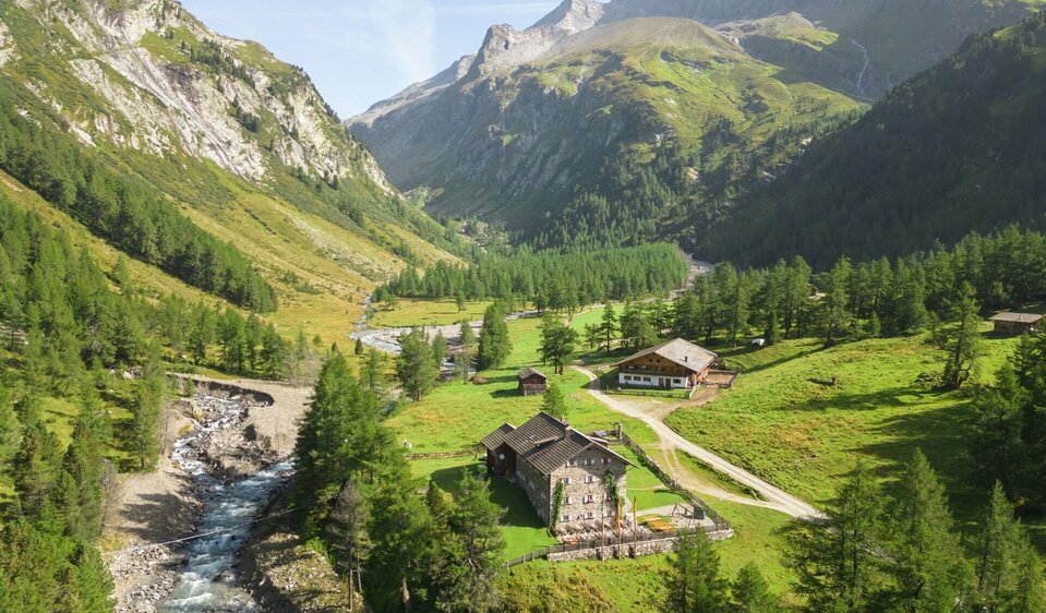 Blick auf Kalser Tauernhaus Blick auf das Kalser Tauernhaus auf der zweiten Etappe der Glocknerkrone in Osttirol. Grüne Almen, der Dorferbach und die Glocknergruppe im Hintergrund.