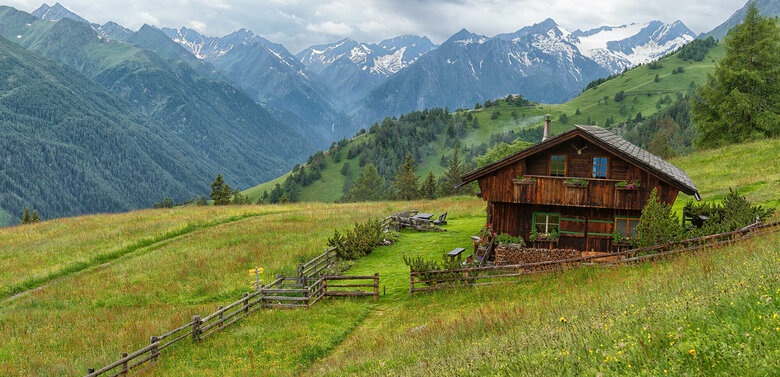 Die urige Gottschaunalm umringt von saftigen Wiesen, mit beeindruckender Bergkulisse im Hintergrund.