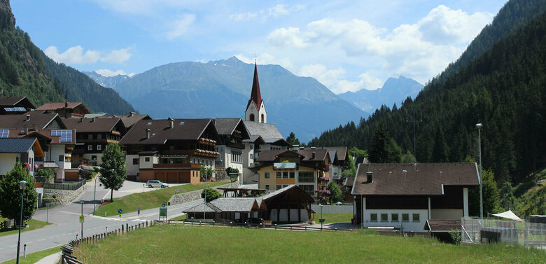 Hopfgarten i. D. im Sommer mit der Kirche und den Bergen im Hintergrund.
