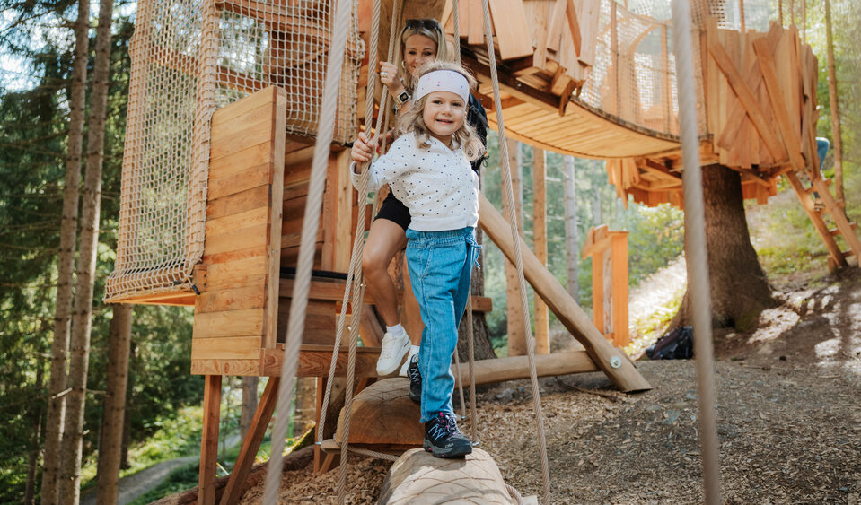 Das Bild zeigt ein Mädchen auf dem hölzernen Klettergerüst im Wichtelpark Sillian.