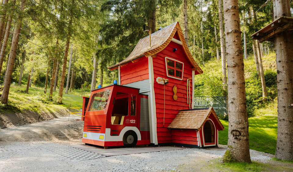 Die Wichtelfeuerwehr, als Kombination aus Feuerwehrauto und Gerätehaus, steht auf einer ruhigen Waldplattform.