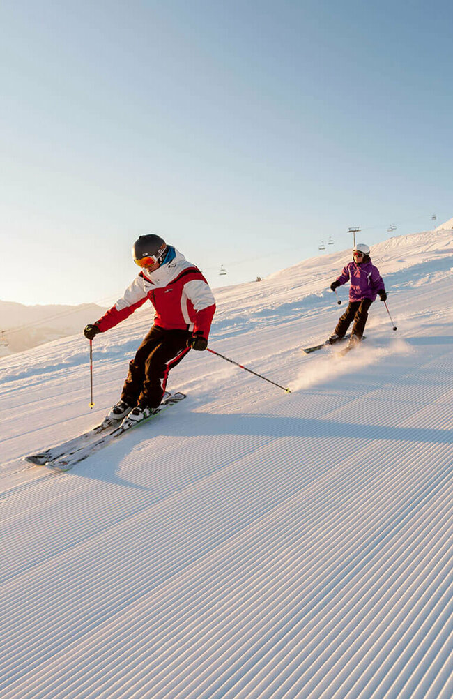 Skifahren Zettersfeld Ein Skilehrer fährt mit mehreren Kindern über eine frisch präparierte Abfahrt im Skigebiet Zettersfeld.
