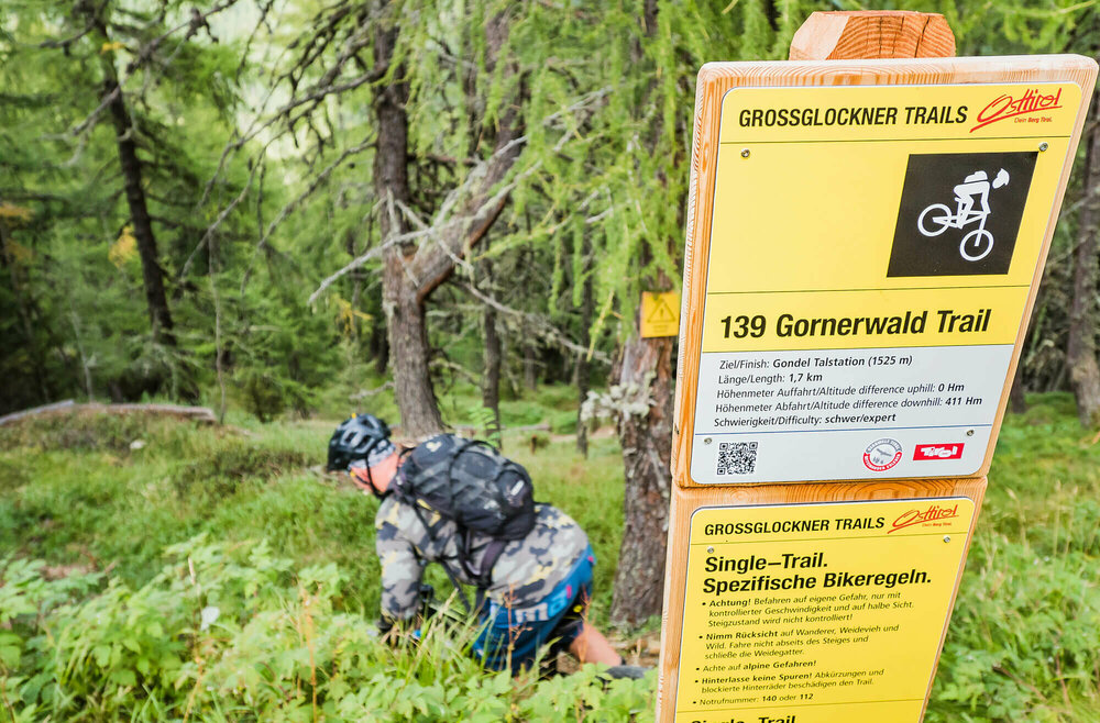 Mountainbiker bei einem Hinweisschild betreffend der Verhaltensreglen beim Biken