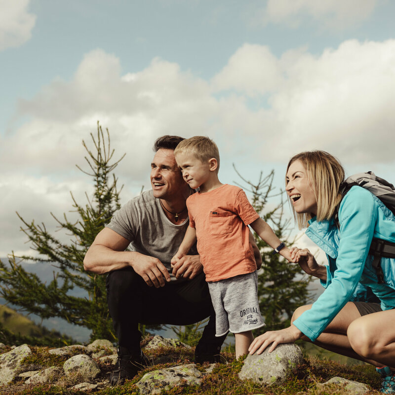 Eine junge Familie schaut gespannt in die Ferne auf der Kindermeile Obertilliach