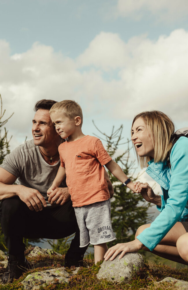 Eine junge Familie schaut gespannt in die Ferne auf der Kindermeile Obertilliach