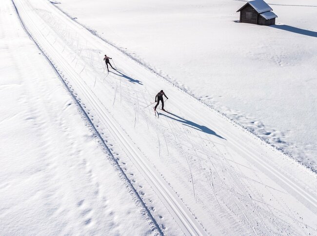 Luftaufnahme von zwei Langläufern auf der Loipe in den Tilliacher Feldern