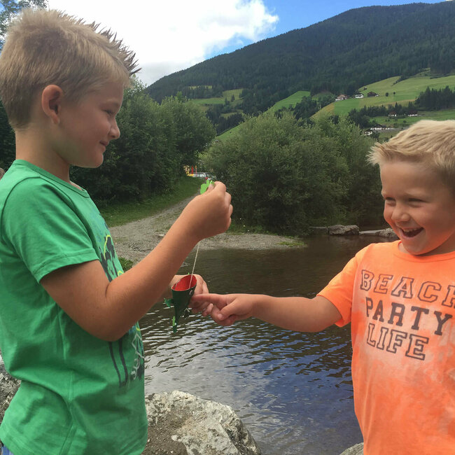 Wichtelwasserwelt Heinfels Zwei Jungs stehen sich gegenüber und spielen mit einem Papierspielzeug.