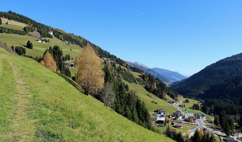 Untertilliach Blick auf Untertilliach aus einer höher gelegenen Lage im Herbst. Auch die alte rosa gefärbte Pfarrkirche am Ende einer steilen Wiese ist zu sehen.