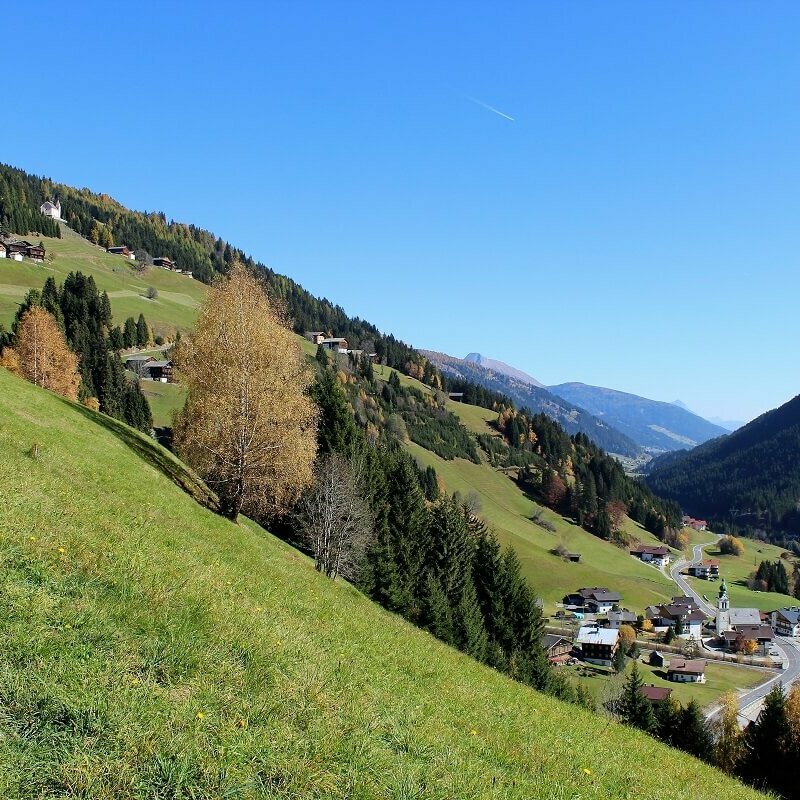 Untertilliach Blick auf Untertilliach aus einer höher gelegenen Lage im Herbst. Auch die alte rosa gefärbte Pfarrkirche am Ende einer steilen Wiese ist zu sehen.
