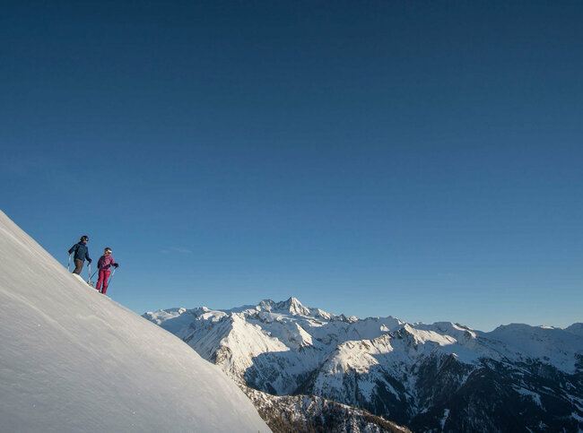 Blick aus der Ferne auf zwei Freerider im Bergpanorama des Großglockner Resort Kals Matrei