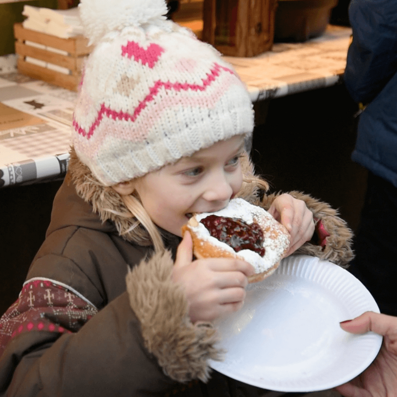 Kind beim Genuss einer Süßigkeit am Lienzer Christkindlmarkt