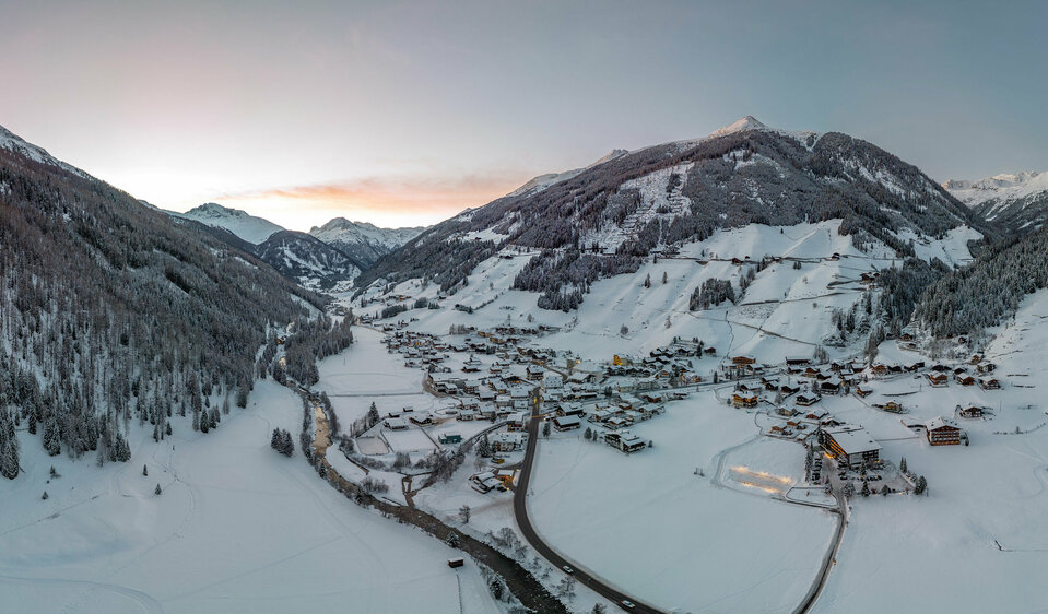 Abendlicher Blick von oben auf das verschneite Dorf St. Jakob im Defereggen im Winter.