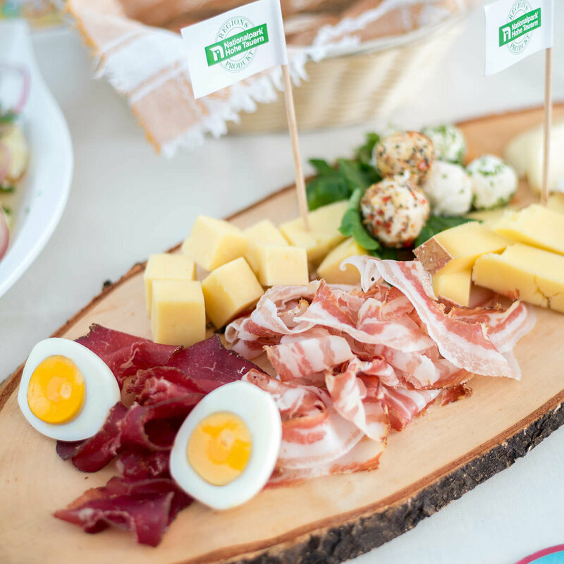 Regionsprodukte Brettljause mit verschiedenen Käsesorten in Würfel geschnitten, feinen Speck- und Henkelescheiben und hartgekochten Eiern.