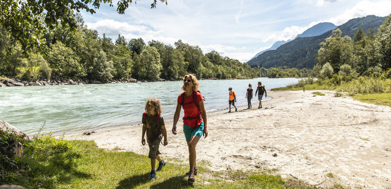 Eine Familie spaziert am Ufer der Isel entlang, auf der 1. Etappe des Iseltrails in Osttirol.