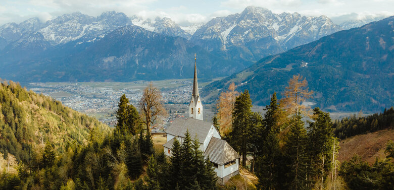 Ausblick auf Helenenkirchl Ausblick auf das Helenenkirchl zwischen den Bäumen im Frühling. Im Hintergrund die Bergkulisse mit Wolken bedeckt.