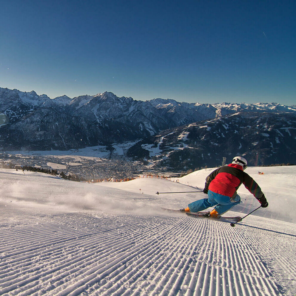 Zettersfeld Lienz Ein Skifahrer mit rot-schwarzer Jacke und blauer Hose zieht seine Spuren im frisch präparierten Skigebiet Zettersfeld in Lienz.