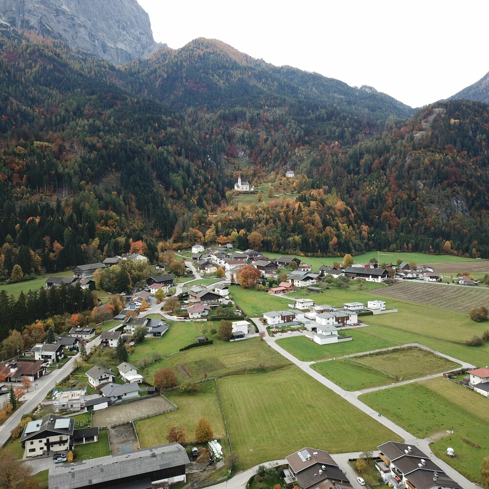 Ortsansicht von Lavant aus Vogelperspektive mit Blick auf die Kirche auf der Anhöhe an einem Herbstag.