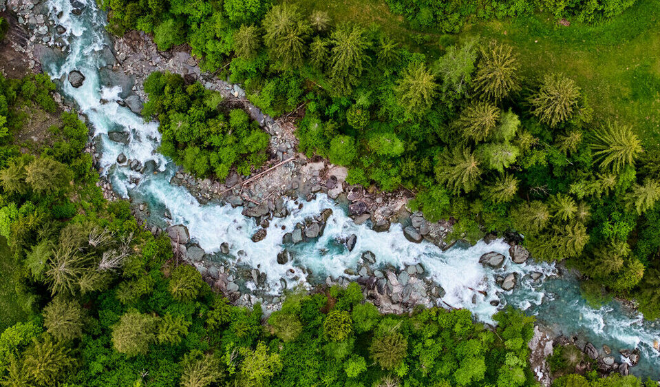 Aus der Vogelperspektive betrachtet, schlängelt sich der blaue Gletscherfluss Isel durch die grüne Umgebung Osttirols.