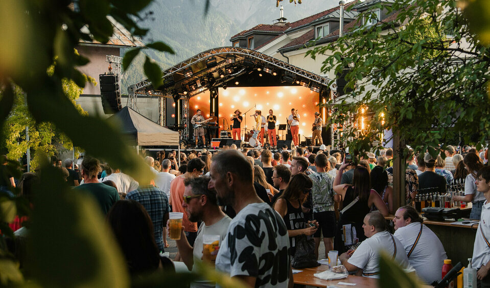 Zu sehen ist die Bühne auf dem Parkplatz Mühlgasse. Vor der Bühne stehen viele Leute und horchen der Band zu.