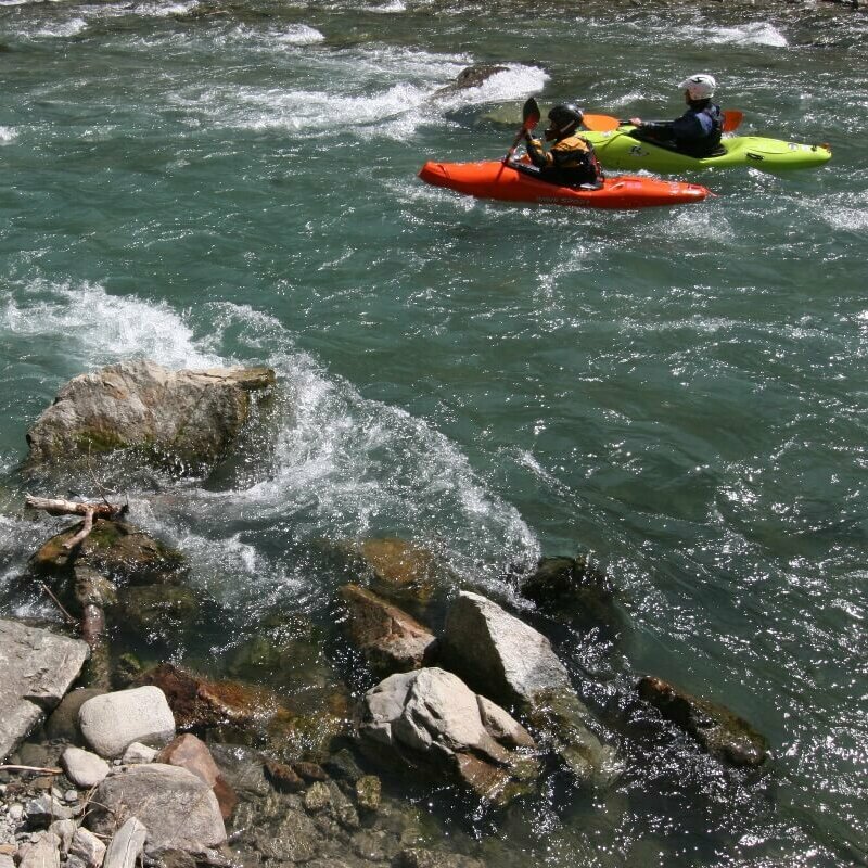 Kajak Schwarzach Zu sehen sind drei Kajakfahrer, die in der rauschenden Schwarzach unterwegs sind. Der Wasserspiegel wird von mehreren Felsen durchbrochen.