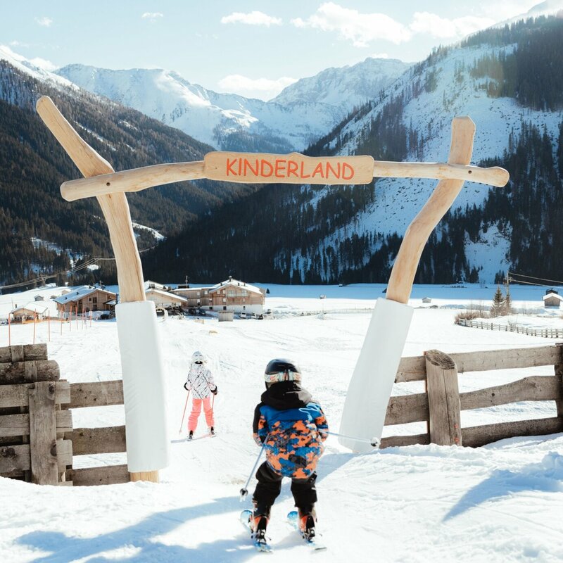 Ein Kind passiert auf Ski den Eingang ins Kinderland im Familienskigebiet Golzentipp in Obertilliach.