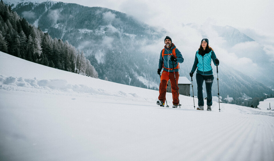 Ein Pärchen wandert auf perfekt präparierten Winterwanderwegen durch Osttirols Winterlandschaft.