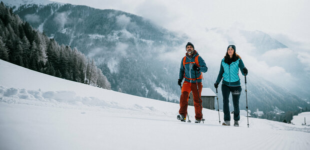 Ein Pärchen wandert auf perfekt präparierten Winterwanderwegen durch Osttirols Winterlandschaft.
