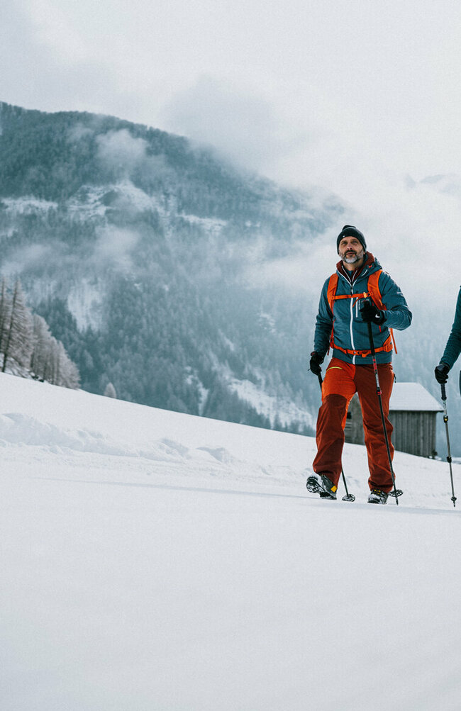 Ein Pärchen wandert auf perfekt präparierten Winterwanderwegen durch Osttirols Winterlandschaft.