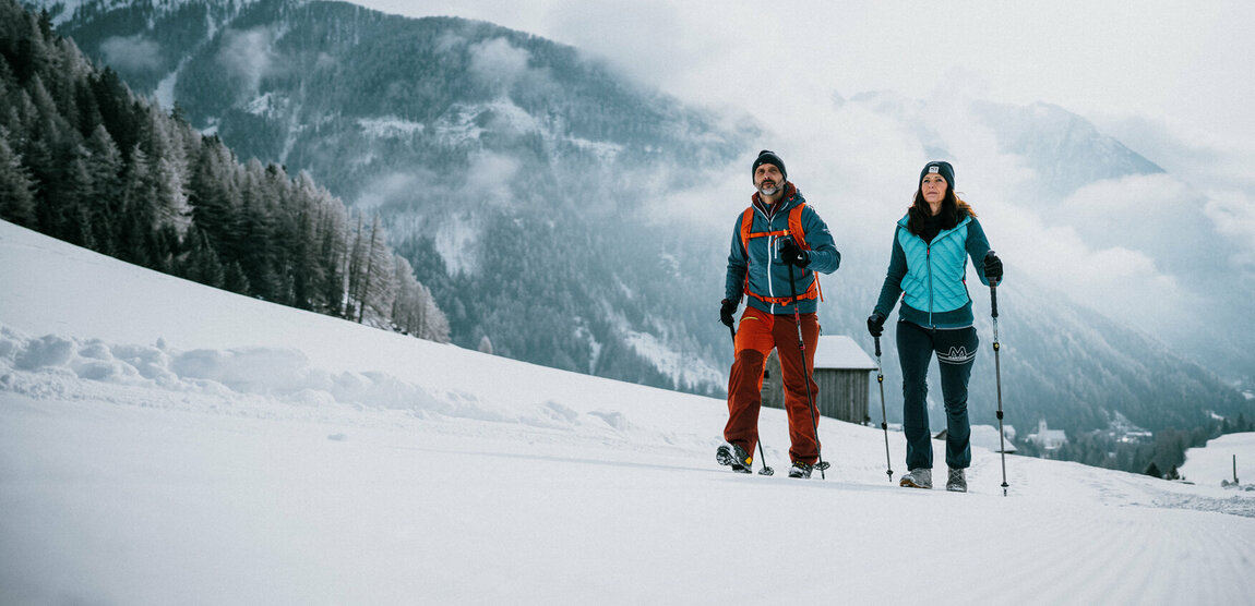 Ein Pärchen wandert auf perfekt präparierten Winterwanderwegen durch Osttirols Winterlandschaft.