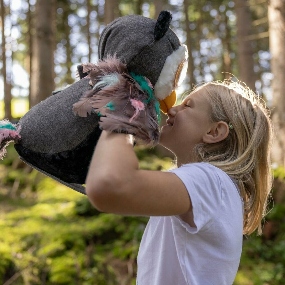 Ein Kind spielt mit Eule Elfi im Wald