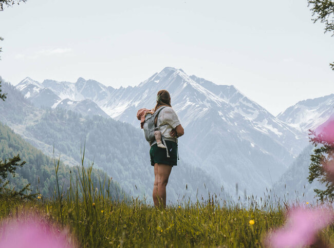 Wandern mit Kind Prägraten Eine Mama steht mit ihrem Kind auf einer Bergwiese in Prägraten in Osttirol.