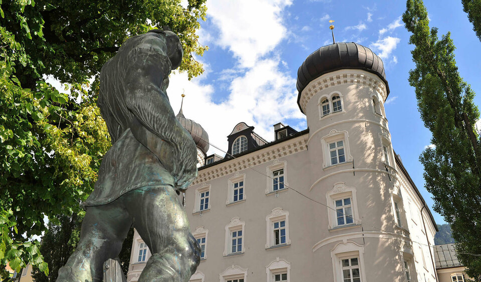 Foto von der Bronzestatue vor der Liebburg in Lienz an einem sommerlichen Tag mit leicht bewölktem Himmel.