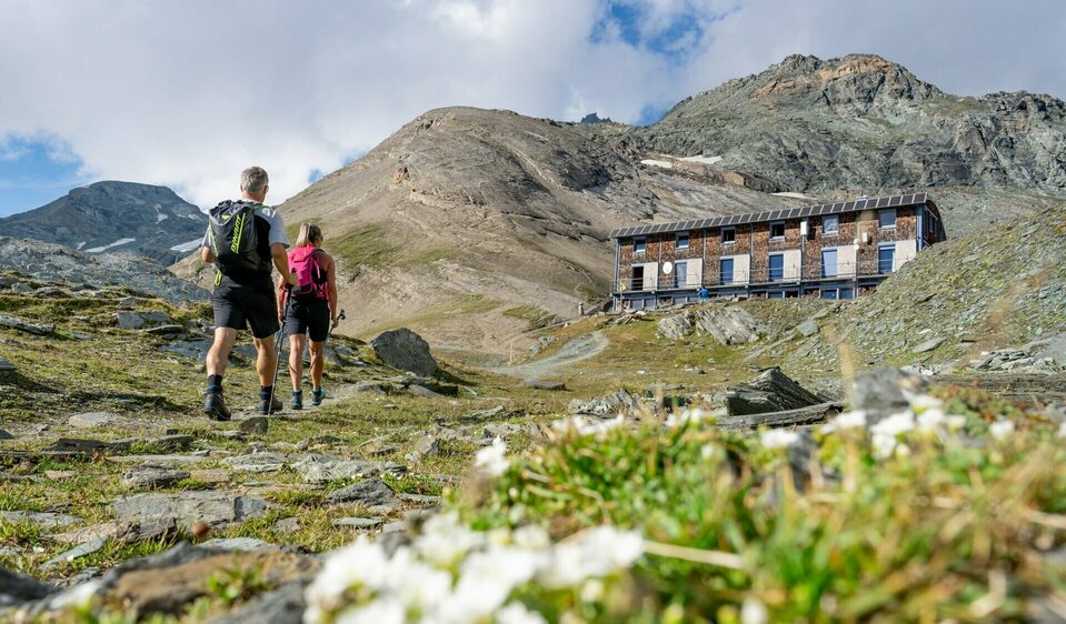Blick auf Stüdlhütte Wanderer auf Etappe 3 der Glocknerkrone in Osttirol nahe Kals am Großglockner mit Blick auf Schutzhütte und Gebirge beim Weitwandern.