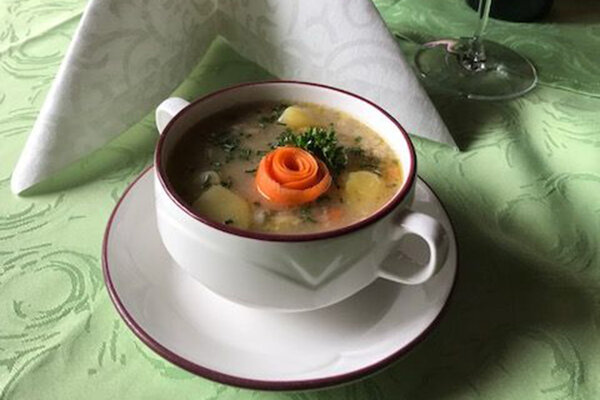 Eine Portion Erdäpfelsuppe mit einer Rose aus Karotten verziert.
