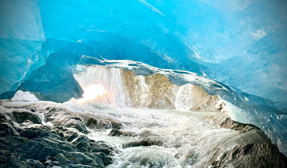 Unter einem Gletscher stehend maßt das Jahrhunderte alte Eis blau an.