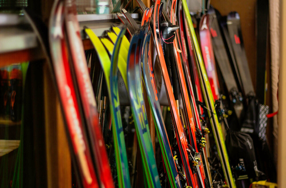 Verschiedene Ski stehen nebeneinander angelehnt an einen Ständer.