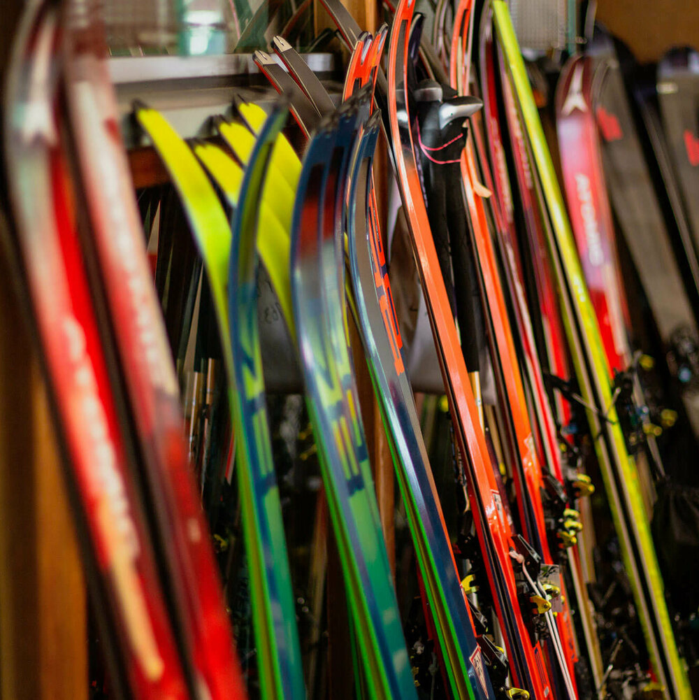 Verschiedene Ski stehen nebeneinander angelehnt an einen Ständer.