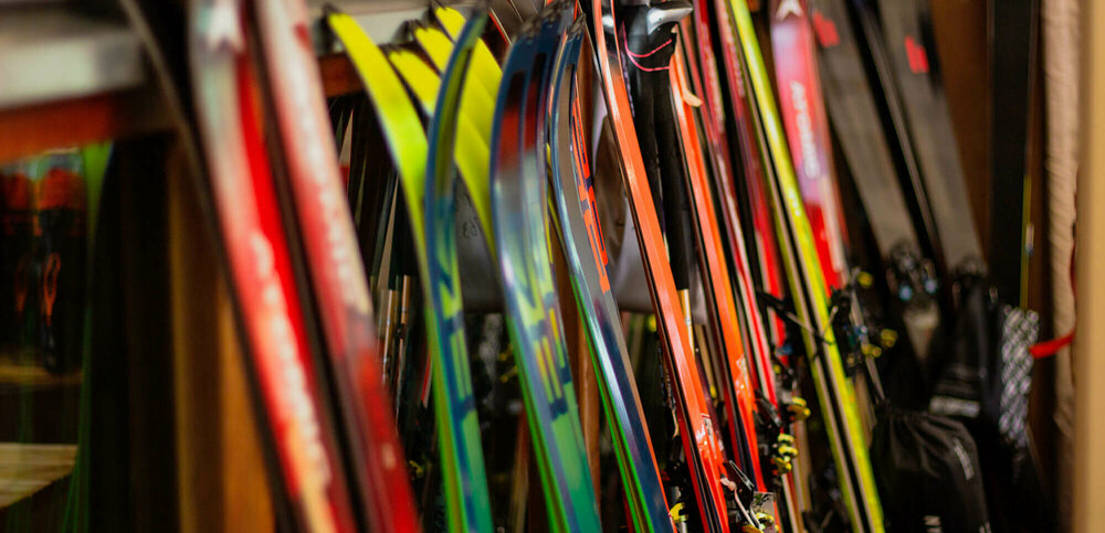 Verschiedene Ski stehen nebeneinander angelehnt an einen Ständer.