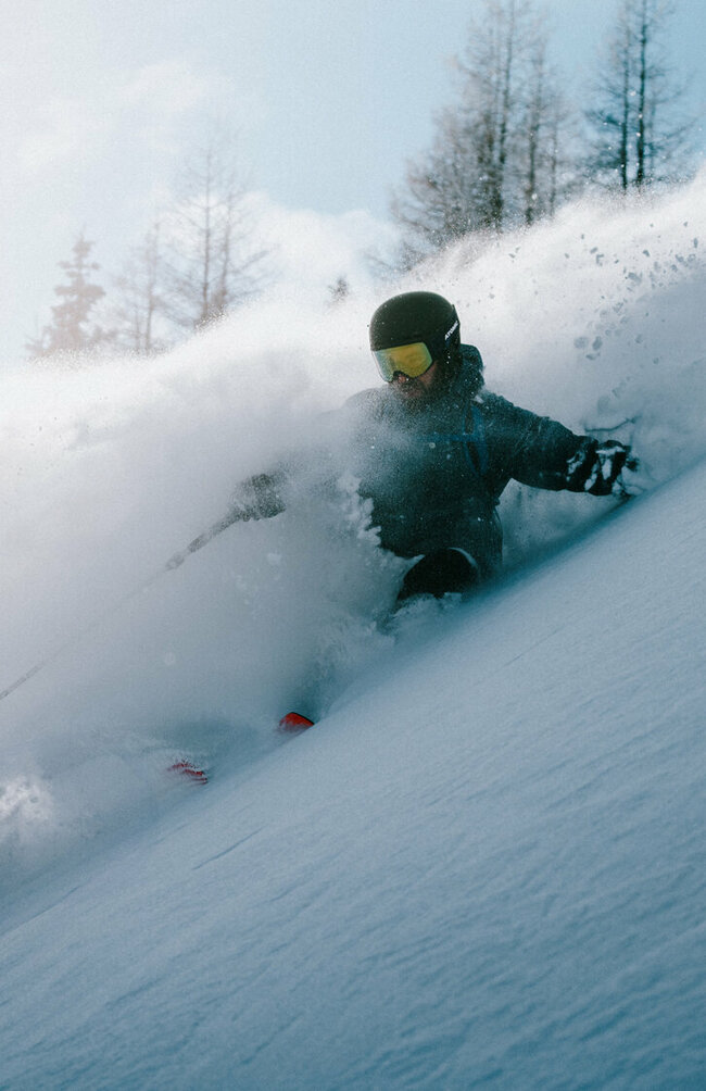 Abfahrten vom Allerfeinsten erwarten dich auf Osttirols Skitourenrouten. Ein Skitourenfahrer bei der Abfahrt von der Roten Wand im Defereggental. Er fährt durch Tiefschnee und Trägt Helm, Skibrille und Stöcke.