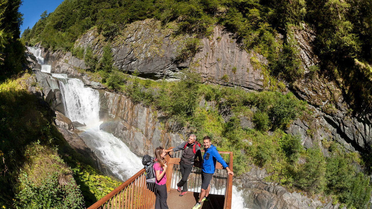 Drei Gäste auf einer Aussichtsplattform vor den Umballfällen.